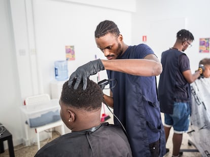 Un joven congoleño, solicitante de asilo, corta el pelo a una persona que ha acudido al Centro Dignidad de la ONG Refugee Support para utilizar este servicio gratuitamente, en Chipre, octubre de 2022.