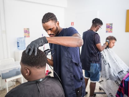 Un joven congoleño, solicitante de asilo, corta el pelo a una persona que ha acudido al Centro Dignidad de la ONG Refugee Support para utilizar este servicio gratuitamente, en Chipre, octubre de 2022.