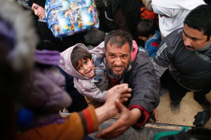 Un iraquí desplazado y su hijo se preparan para subir a un camión para ser llevados a un lugar seguro, en Mosul, Irak.