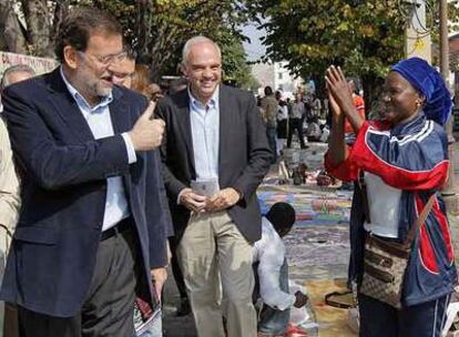 El presidente del PP, Mariano Rajoy, saluda a una vendedora callejera durante su visita a San Froilán, (Lugo).