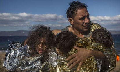 Un hombre sostiene a tres niños que se protegen con mantas térmicas a su llegada a la isla griega de Lesbos el 28 de octubre.