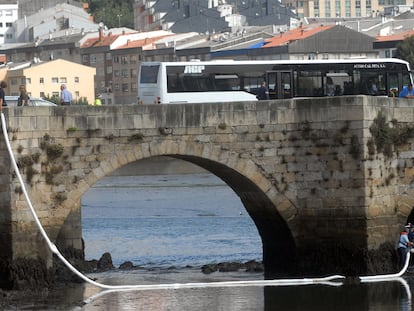 Varios agentes colocan barreras para frenar la mancha de combustible a la altura del puente romano de O Burgo.