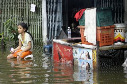 Un niña sentada fuera de su casa en Bangkok