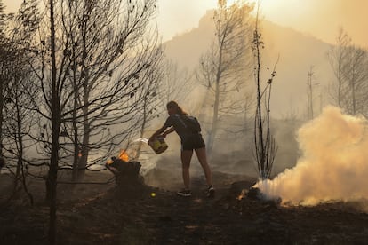 Marina Kalogerakou, de 24 años, utiliza un balde para intentar extinguir un foco de fuego en Penteli, este lunes.