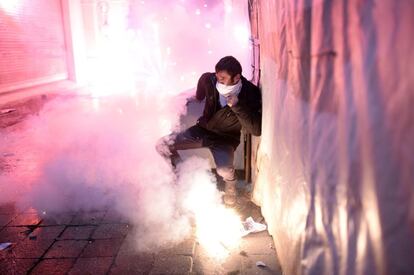 Un manifestante turco se protege de los fuegos artificiales que estallan en la avenida Istiklal durante los enfrentamientos entre la policía turca y manifestantes. La corrupción de alto nivel con la participación de estrechos aliados del gobierno ha llevado a una nueva efusión de ira contra el gobierno del primer ministro.
