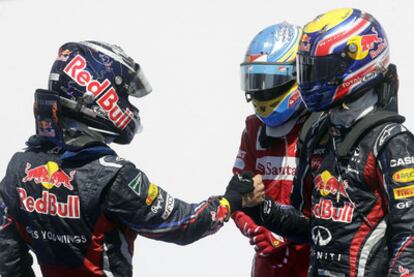 Vettel, a la izquierda, se saluda con su compañero Webber en presencia de Fernando Alonso.