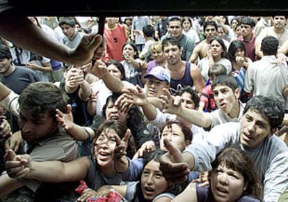 Un grupo de argentinos recibe alimentos repartidos por el dueño de un supermercado para evitar un asalto.