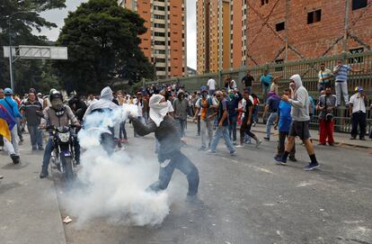 Un manifestante opositor devuelve una lata de gas lacrimógeno durante las protestas de este miércoles en Caracas.