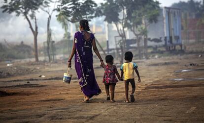 Una mujer y sus hijos caminan con un cubo hacia las letrinas a las afueras de Bombay, en India.