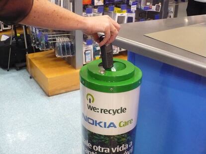 Un ciudadano deposita un móvil usado en un contenedor de reciclaje en Bilbao.