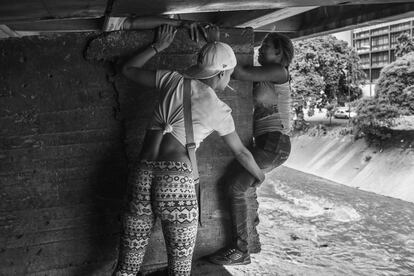 Inés ayuda a una compañera a salir de debajo del puente de la autopista Francisco Fajardo donde están viviendo.


