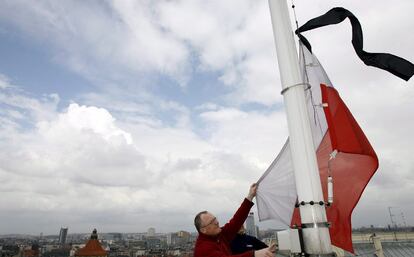 Un hombre iza a media asta y con un crespón negro la bandera nacional polaca de la sede del gobierno de la provincia de Silesia como muestra de duelo por la muerte en accidente aéreo. El presidente del Parlamento polaco ha asumido la jefatura del Estado de manera interina, hasta que se celebren las nuevas elecciones en un par de meses.