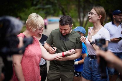 El presidente ucranio firma un autógrafo en el brazo de una mujer mientras visita un sanatorio de Zaporiya en el que actualmente viven civiles que se vieron obligados a dejar sus casas por los bombardeos rusos.