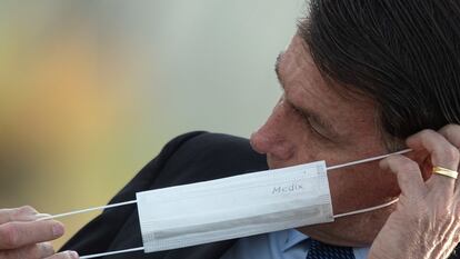 El presidente de Brasil, Jair Bolsonaro, se coloca una mascarilla durante una ceremonia oficial.