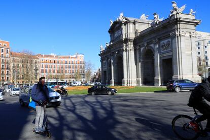 Un hombre circula en un patinete eléctrico por la calzada en la rotonda de la Puerta de Alcalá de Madrid.