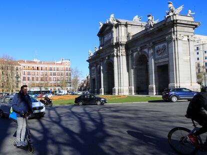 Un hombre circula en un patinete eléctrico por la calzada en la rotonda de la Puerta de Alcalá de Madrid.