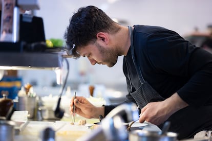 Un cocinero terminando un plato en la cocina de Els Casals.