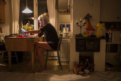 Elderly woman by table in small cottage