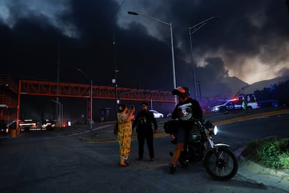 Un oficial de policía habla da indicaciones a una mujer cerca de uno de los siniestros en las afueras de Monterrey, en Santa Catarina.