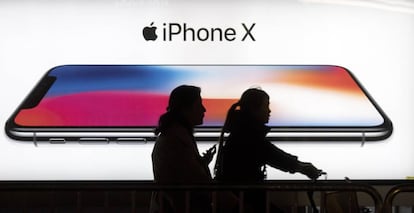 Dos personas pasan por delante de un anuncio del iPhone X.