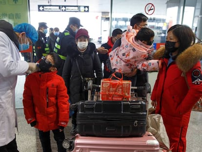 Médico mede a temperatura de passageiros antes do embarque no aeroporto de Changsha, na China.