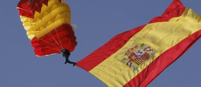 Un paracaidista despliega una bandera española durante el desfile.