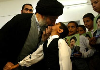 El clérigo chií Mohamed Baqer al Hakim besa a un niño en la sede de su partido ayer en Nayaf.
