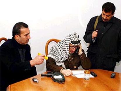 Arafat, entre sus guardaespaldas, habla por teléfono esta mañana desde su cuartel general en Ramala.