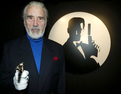 El actor británico Christopher Lee, posa con la pistola original ante un cartel de la película 'El hombre de la pistola de oro' (1974), en la que interpretaba el papel del malvado Scaramanga, en octubre de 2002.