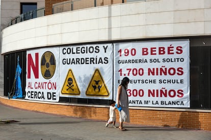 Una mujer y un niño pasan por delante de una de las muchas pancartas contra el cantón del barrio de Montecarmelo.