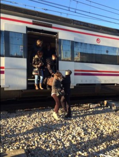 Un policía ayuda a bajar a los pasajeros del tren desalojado por amenaza de bomba.