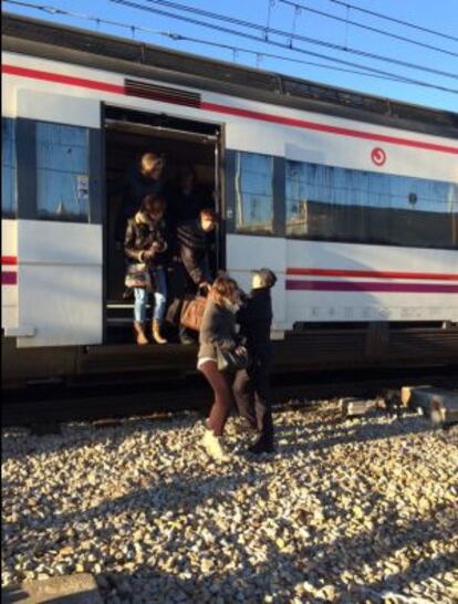 Un policía ayuda a bajar a los pasajeros del tren desalojado por amenaza de bomba.