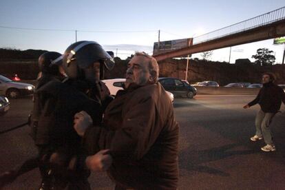 Un agente de Polica Nacional contiene a un hombre que trata de detener el trfico en la avenida de Alfonso Molina, principal va de salida de la ciudad de A Coru?a. Con gritos contra el desalojo, los manifestantes permanecen en la zona, mientras una excavadora se encuentra en las inmediaciones de la vivienda.