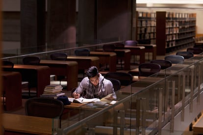Un joven estudiando en una biblioteca.
