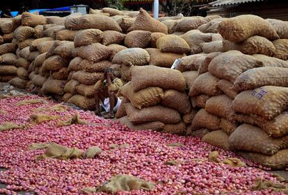 Un vendedor de cebollas espera clientes, en un mercado de Bangalore (India).