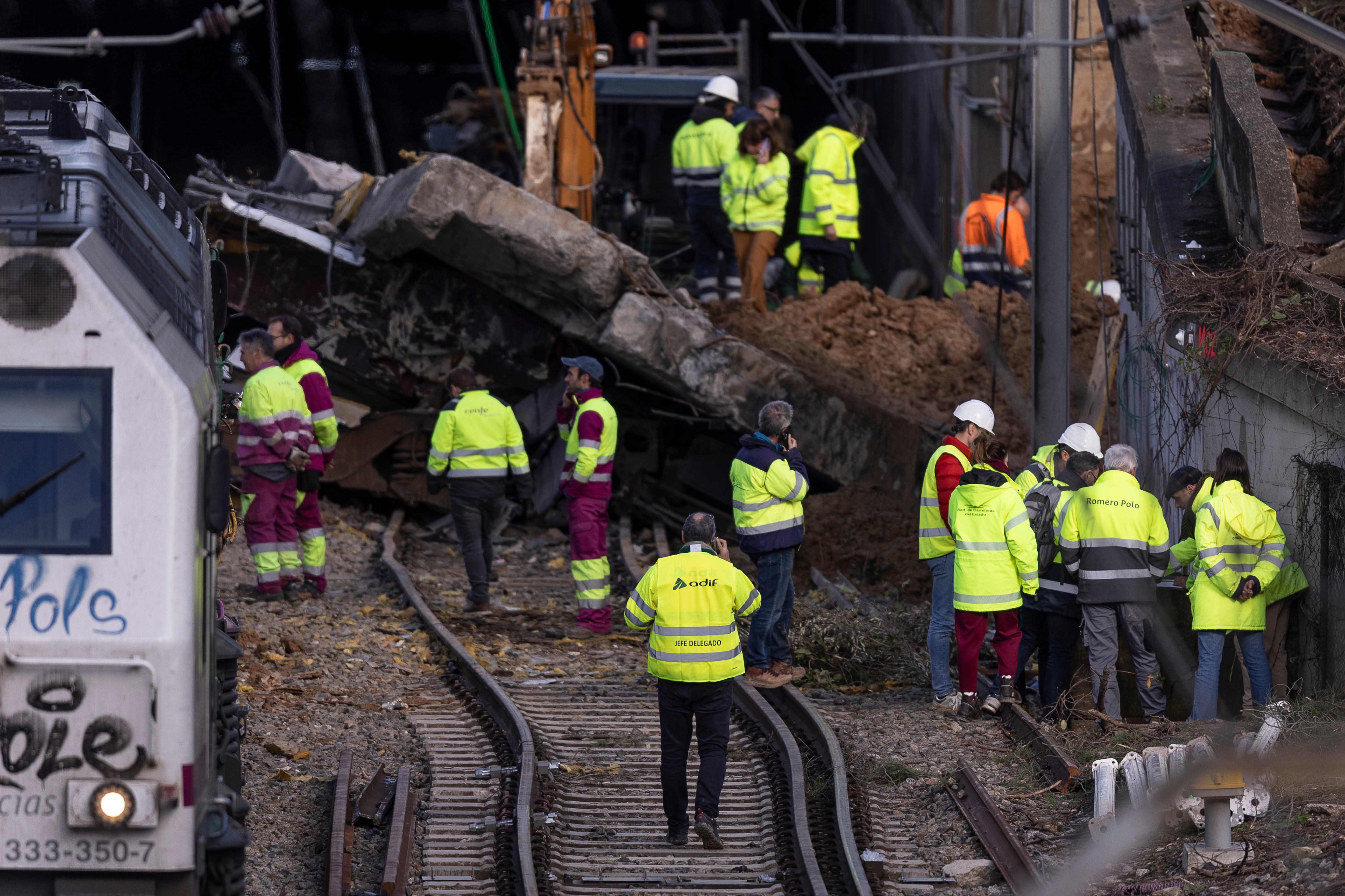 Operarios de Adif, RENFE y de la Red de Carreteras del Estado, este domingo en las obras de reparación en el lugar donde el tren colisionó con el talud de la autopista AP-7.