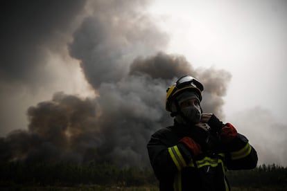 Un bombero ajusta su casco mientras monta guardia para monitorear el incendio, este jueves.