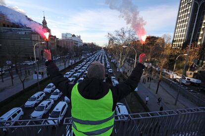 Decenas de grúas han retirado esta mañana en el paseo de la Castellana taxis mientras que los agentes municipales multaban, con hasta 200 euros, a sus conductores. En la imagen, un taxista sujeta unas bengalas durante la protesta.