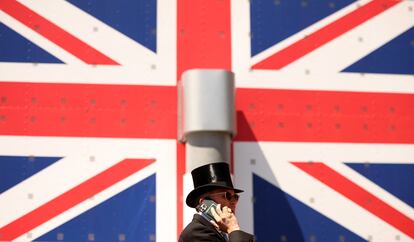 Un asistente habla por teléfono delante de la bandera de Reino Unido, conocida como la Union Jack. 