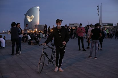 Un joven camina con su bicicleta en el paseo marítimo de la Barceloneta.