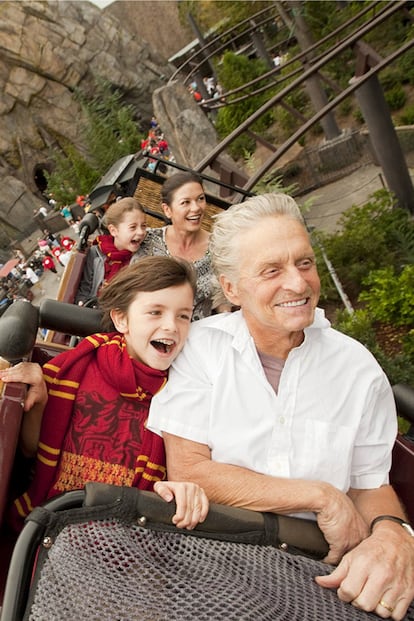 Michael Douglas disfrutando con sus hijos, Dylan y Carys, a bordo de una montaña rusa en un conocido parque de atracciones.