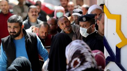 Un policía hace guardia mientras los habitantes esperan fuera de un banco, en la ciudad de Gaza, el pasado 29 de marzo.