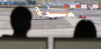 Dos personas observan uno de los aviones de Iberia en Barajas.