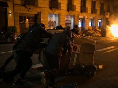 Un grupo de manifestantes mueve un contenedor de basura durante los altercados en el centro de Barcelona, el 17 de febrero.