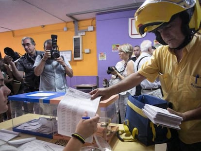 Un cartero entrega el voto por correo en una mesa de un colegio electoral de L'Hospitalet de Llobregat (Barcelona), en las elecciones generales de 2016. 