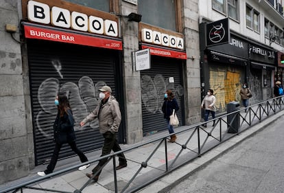 Varias personas caminan por una cale del centro de Madrid ante negocios cerrados.