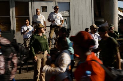 Agentes del Instituto Nacional de Migración de México hacen guardia mientras los migrantes caminan en una caravana a través de un puesto de control en Viva México, Chiapas.