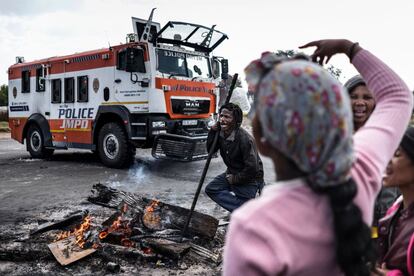 Un manifestante lleva gasolina en una botella de plástico atada a una barra de metal durante una protesta en Matholesville, cerca de Johannesburgo.