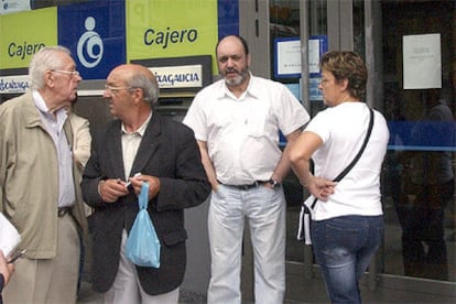 Varias personas permanecen a las puertas de la sucursal de Caixa Galicia atracada esta mañana.