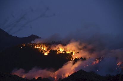 Las llamas se muestran de forma espectacular al caer la noche, avivadas por el viento racheado y quemando un denso pinar en la zona de Montaña de Enrique, en el incendio forestal declarado este lunes en el municipio palmero de El Paso.